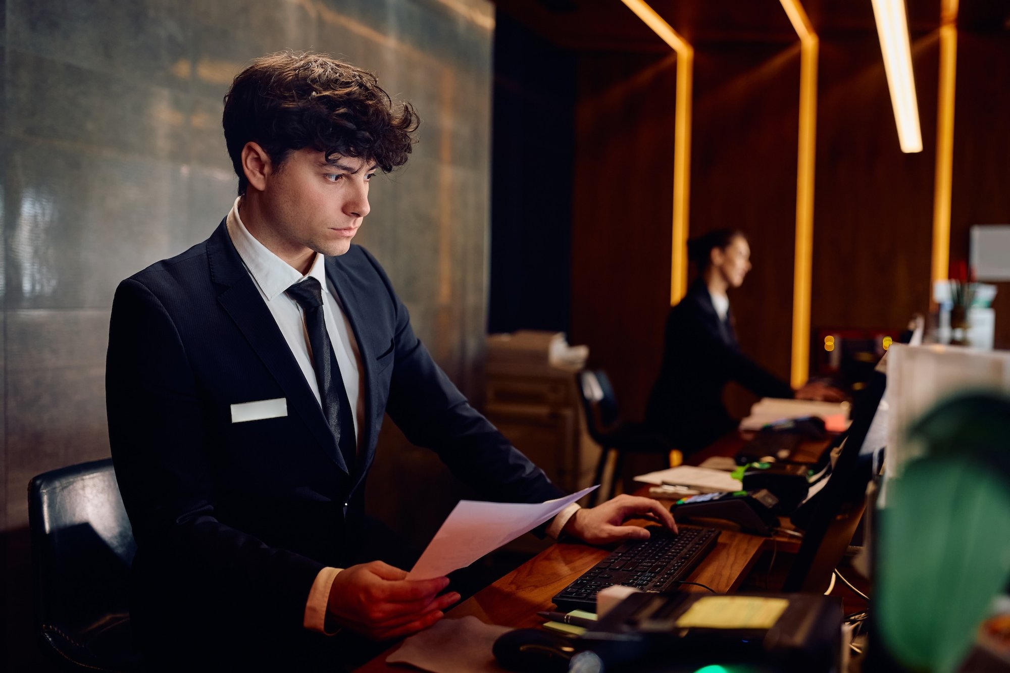 male-receptionist-working-on-desktop-pc-at-hotel-f-2026-01-06-10-29-31-utc